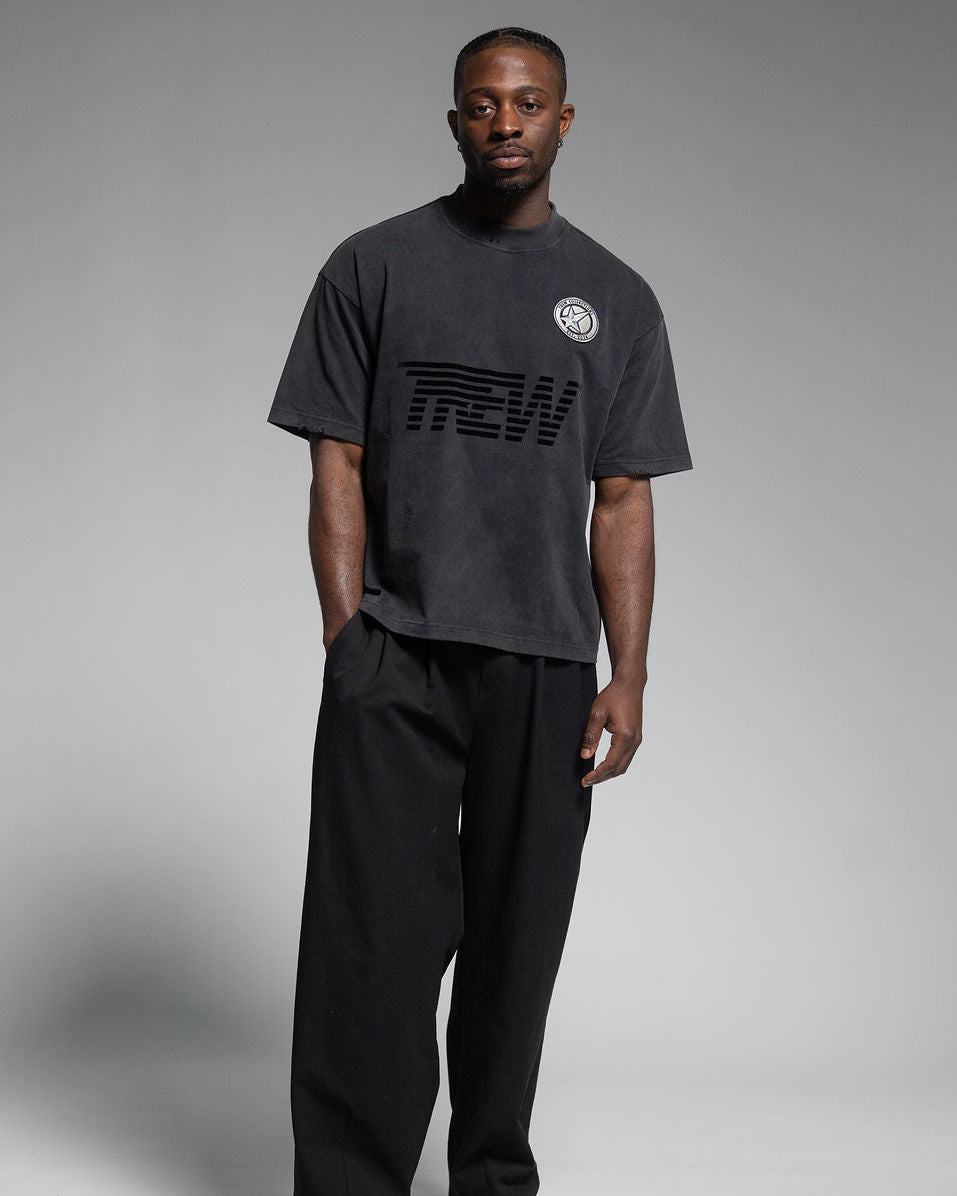 Front facing model wearing Trew Collections Tee against Grey back drop.