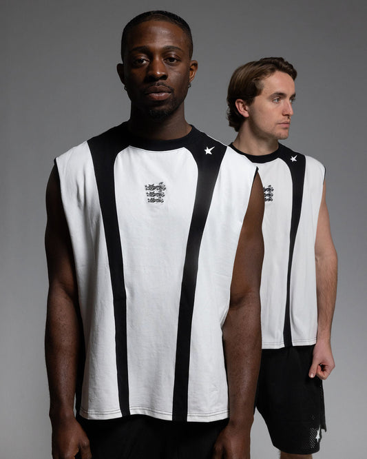 Two models wearing sleeveless white athletic jerseys with black side panels and black shorts, standing against a dark gray studio background.