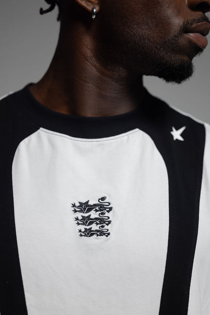 Close-up of a person wearing a black and white training singlet with a black embroidered England lion crest on the chest and a white star logo on the shoulder.
