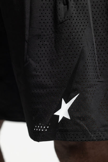 Close-up of black athletic shorts with a perforated texture and a white star logo near the hem.