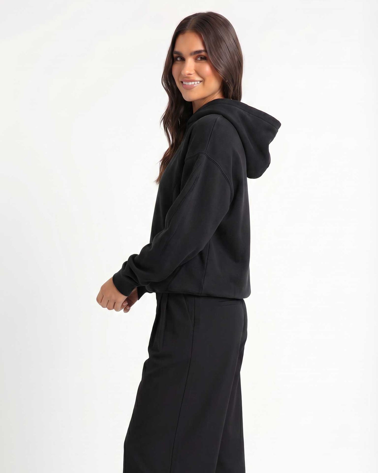 A woman modeling Trew Collections Black on Black hooded sweatshirt against a plain white studio background.